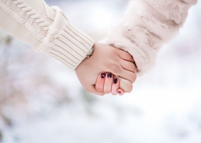 Close Up Of Two People Holding Hands Warmly Outdoors