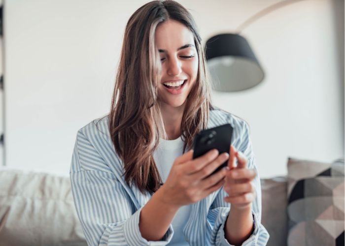 A Happy Woman Looking At Smartphone Screen
