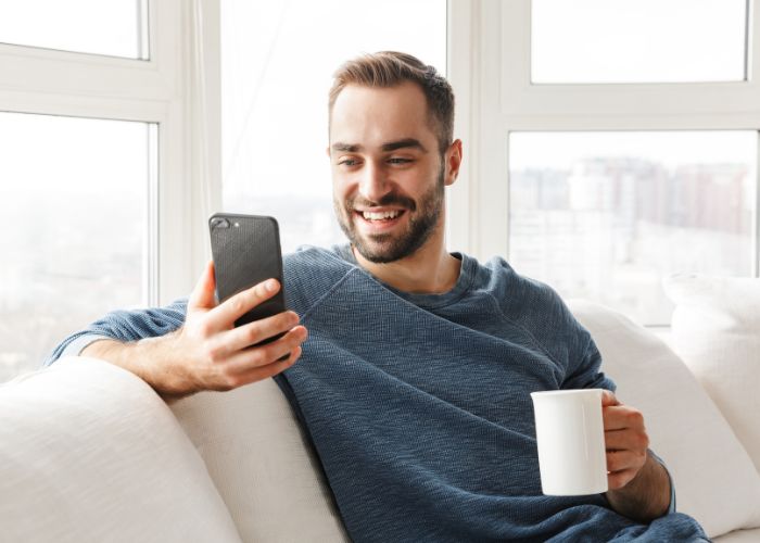 Happy Man Using Phone At Home