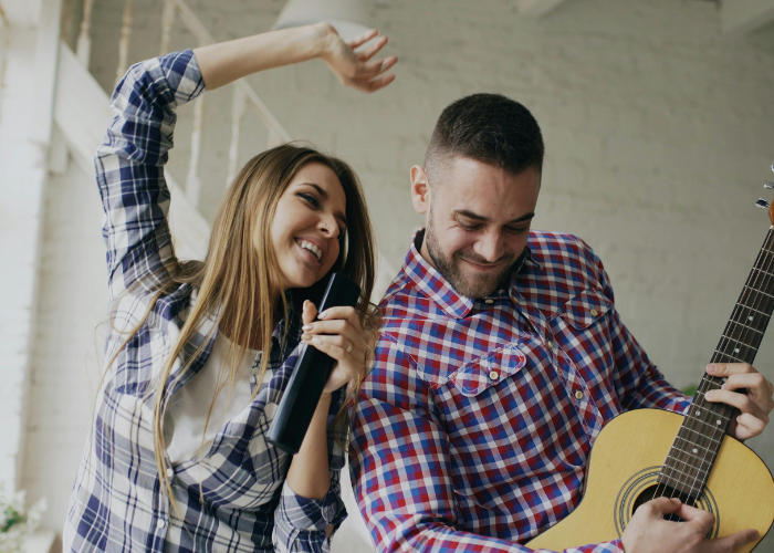 Happy Couple Singing And Playing Guitar Together During A Fun Date.