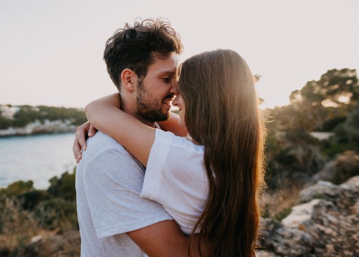 Couple Embracing Outdoors Near Water During Sunset