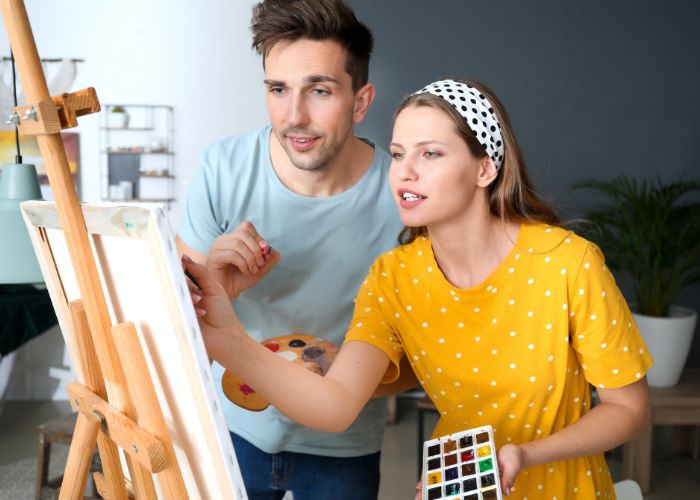 Couple Painting Together At An Easel And Having Fun With Art