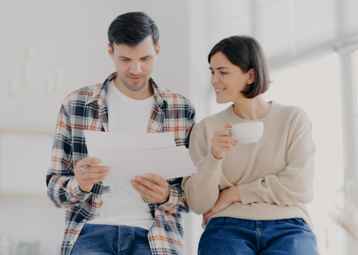 Couple Looking At A Sheet Of Paper Together While Relaxing At Home.