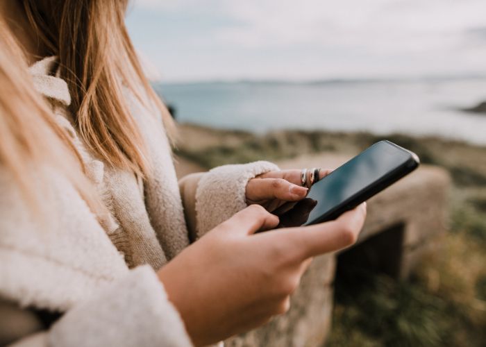 Woman Holding A Smartphone Near The Coast