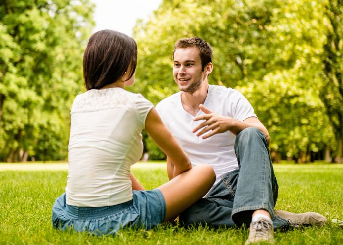 Young Couple Talking While Sitting Together On The Grass
