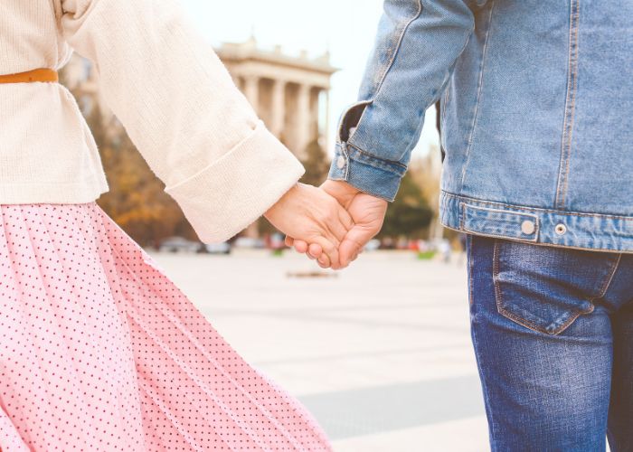 Couple Holding Hands While Walking Together Outdoors On A Sunny Day.