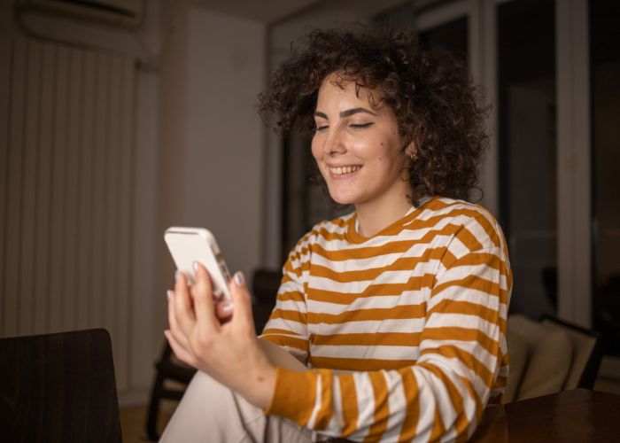 Young Happy Woman Using A Phone At Home