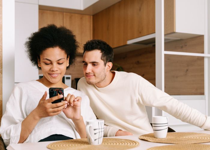 Man And Woman Sitting At Table And Looking At The Phone
