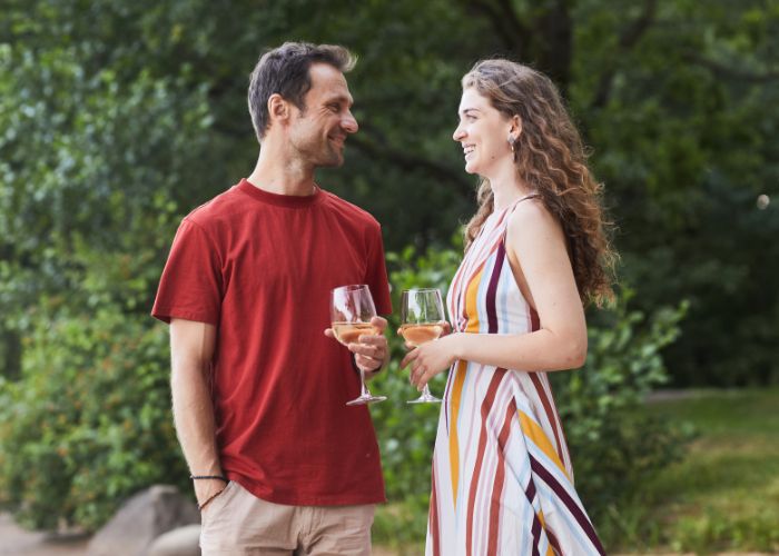 Couple Smiling And Holding Wine Glasses Outdoors
