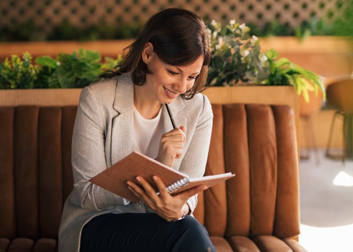 Woman Writing In A Notebook, Reflecting On Personal Goals And Independence.