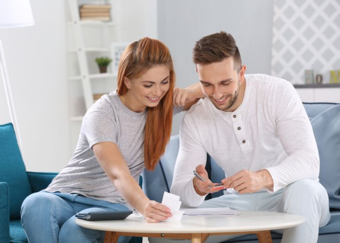 Couple Sitting Together At Home While Reviewing Bills And Planning Their Finances.