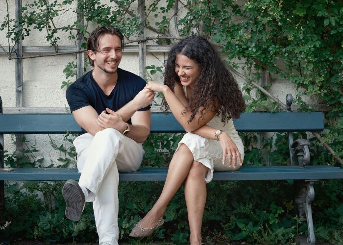 Happy Couple Laughing On A Park Bench