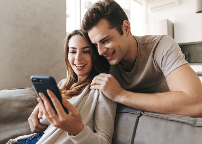 Couple At Home Using Phone