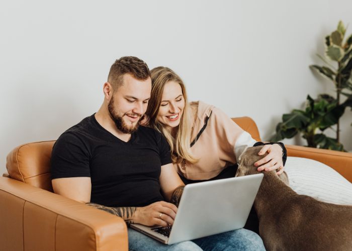 Smiling Couple Relaxing On A Sofa With A Laptop