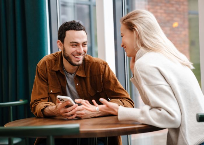 Happy Newly Couple Talking While Sitting In Cafe Indoors