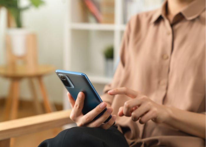 Woman Sitting Indoors Using A Smartphone