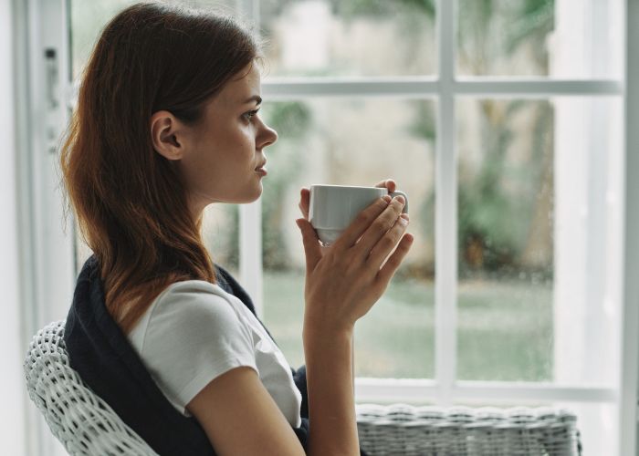 Woman Sitting By A Window Holding A Cup