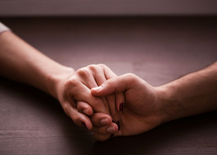 A Couple Holding Hands On A Table