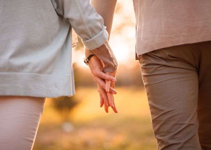 Couple Holding Hands While Walking Together Outdoors In Warm Evening Light.