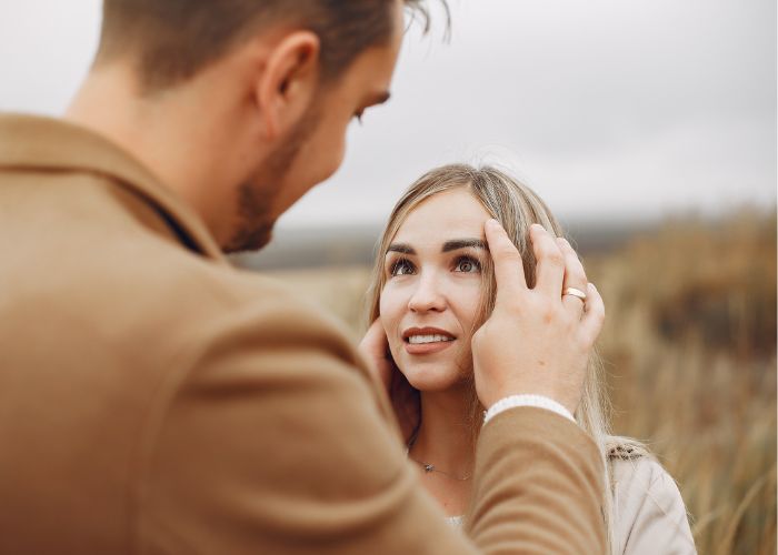Man Gently Touches A Woman’s Face During A Tender Moment Outdoors