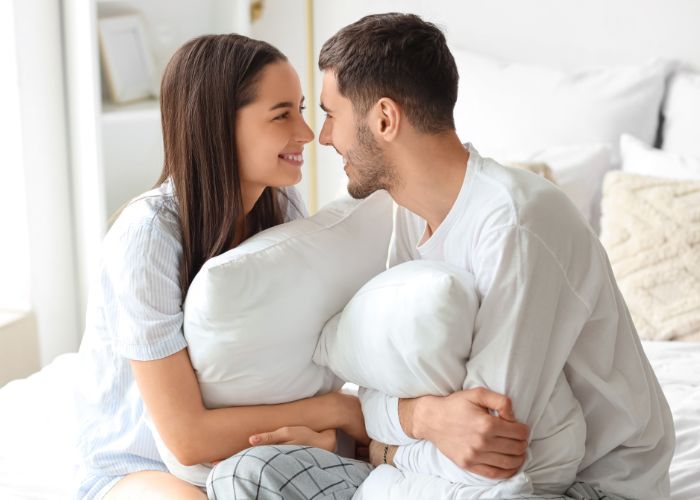 Couple Sitting On A Bed With Pillows