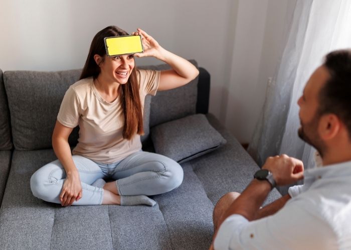Woman Holds A Phone To Her Forehead While Playing A Guessing Game