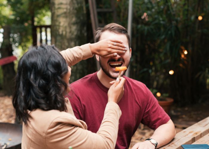 Couple Enjoying A Blind Taste Test Game Outdoors